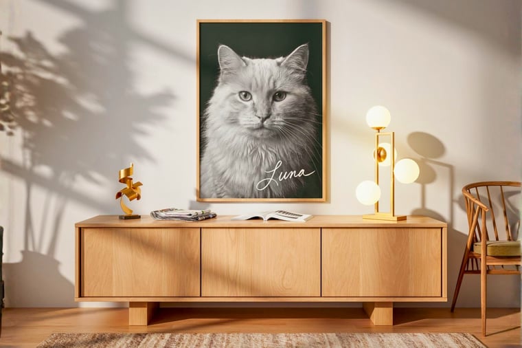 A custom black-and-white cat portrait titled Luna, framed in light oak and hung above a wooden sideboard in a sunlit living room.